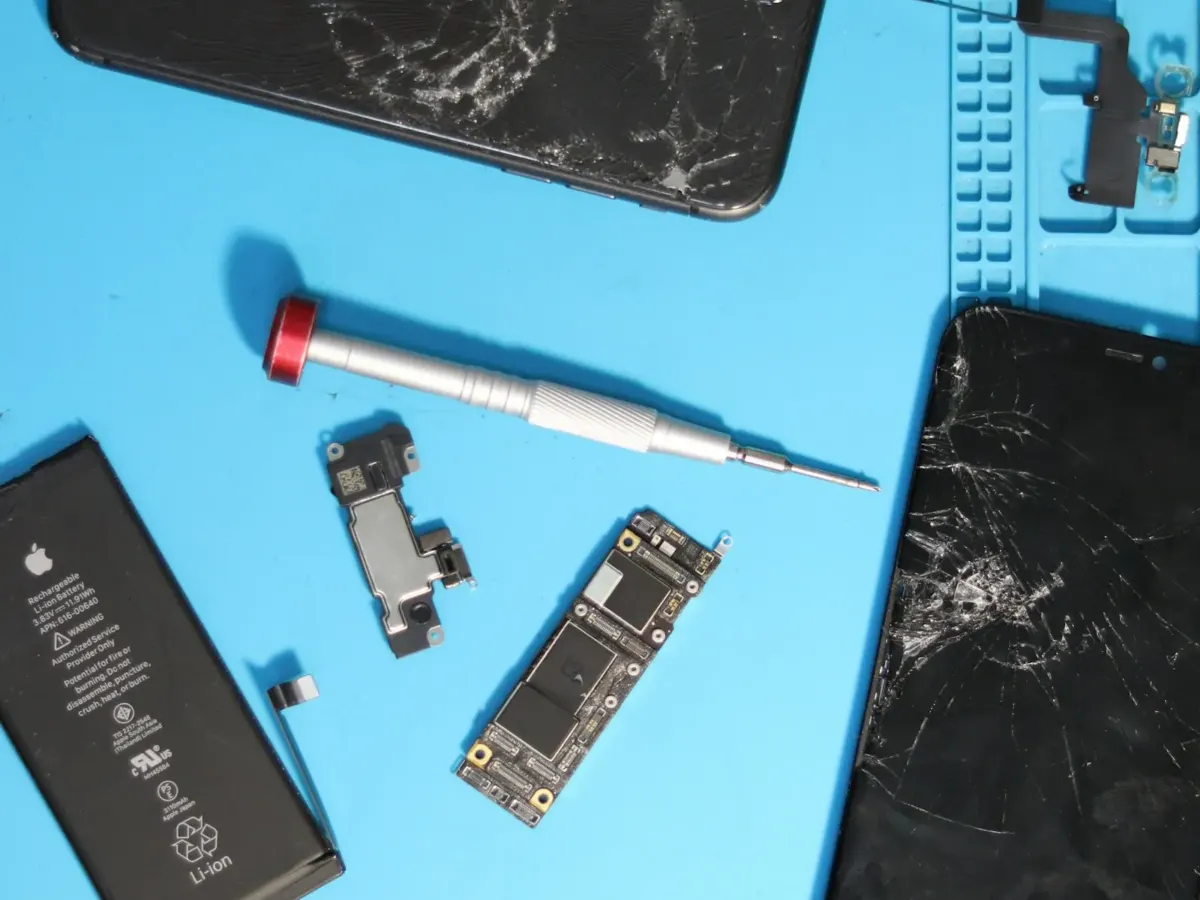 Écrans d’iPhone cassés et outils de réparation sur un tapis d’atelier