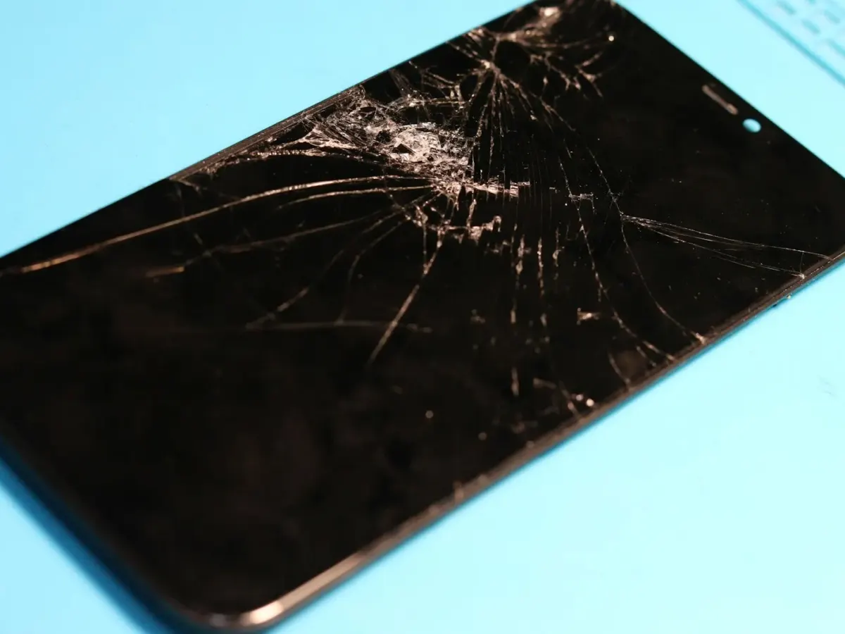 Écran d’iPhone fissuré posé sur un tapis de réparation