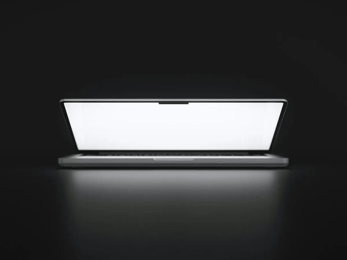MacBook ouvert, écran allumé sur fond sombre