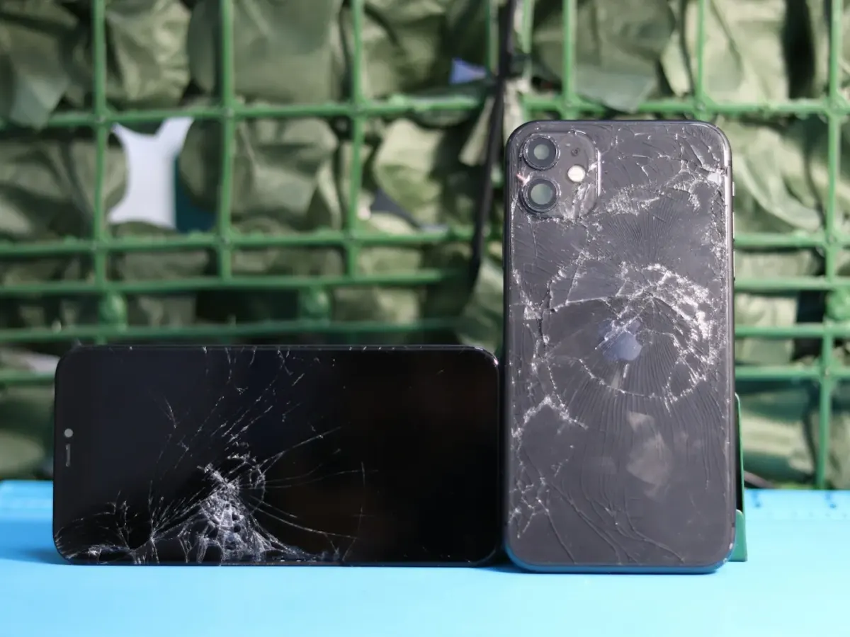 iPhone avec la vitre arrière fissurée, à côté d’un iPhone à l’écran cassé